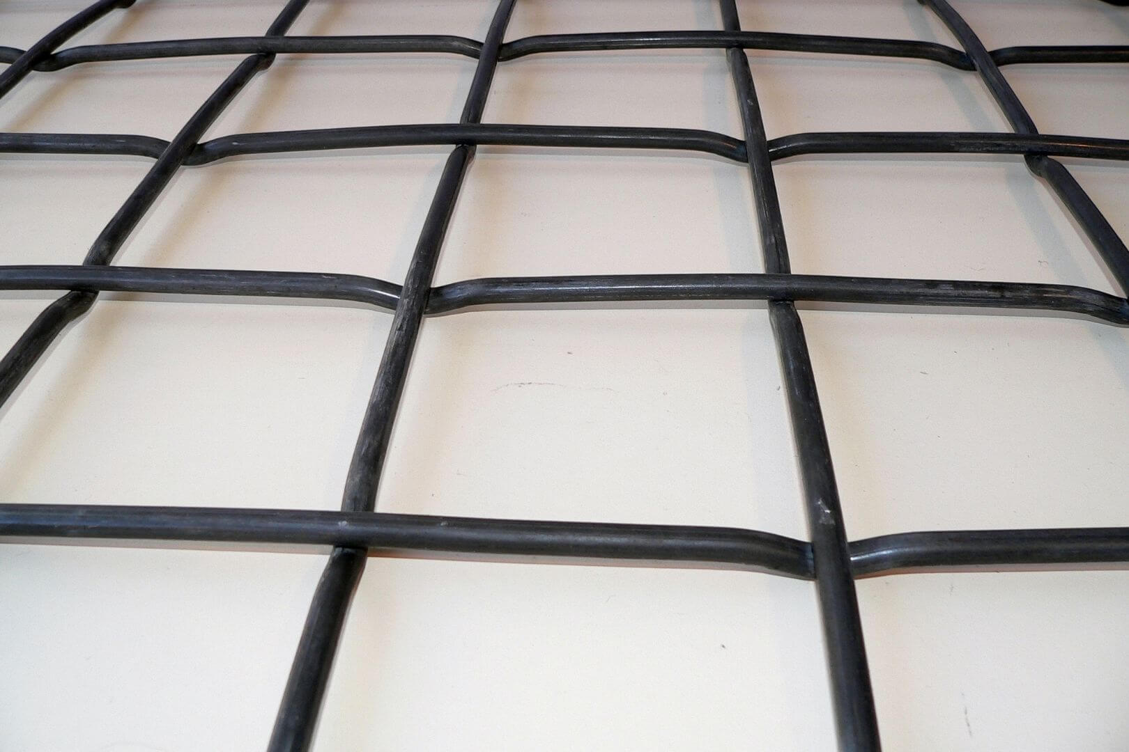 Detailfoto van flat top voorgolfd gevlochten rooster met zware zwarte metalen draden voor industriële roosters, zeefgaas en maatwerktoepassingen.