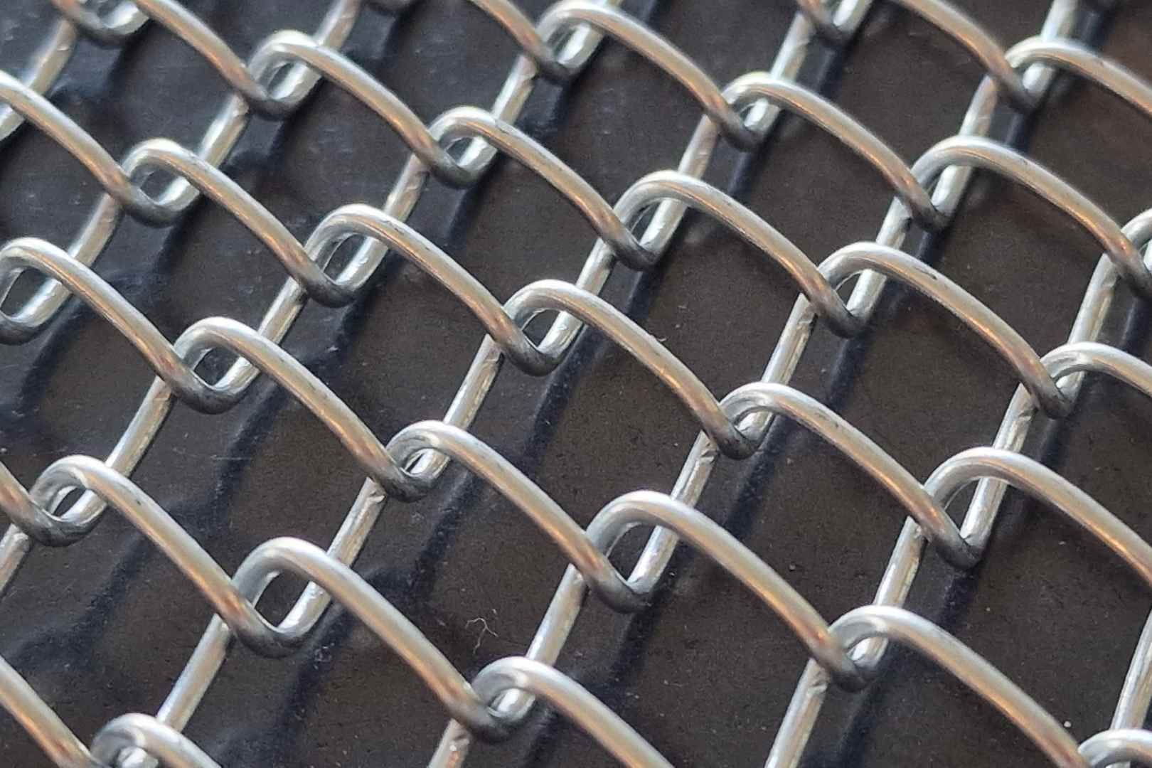 Close-up van een metalen spiraalgordijn met open geweven draadstructuur voor architecturale toepassingen en decoratieve afscheiding