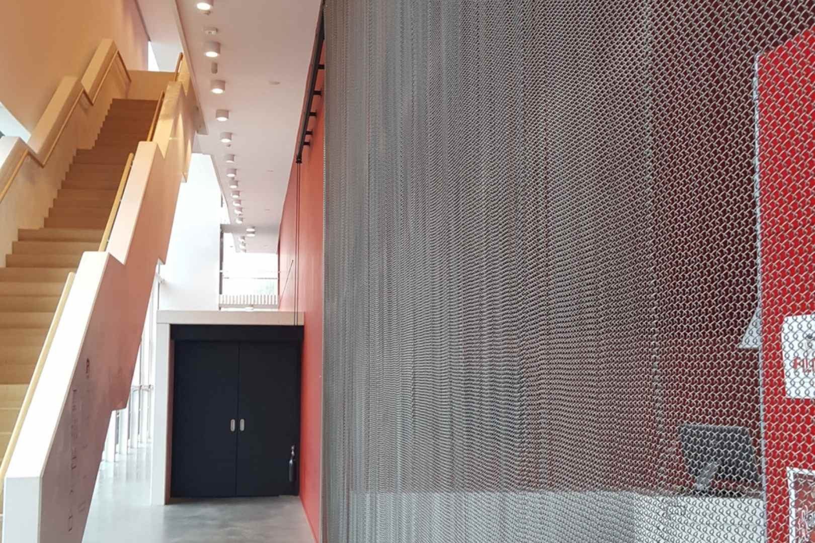 Metalen spiraalgordijn als decoratieve wandbekleding en afscherming in een architecturaal interieur
